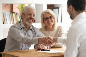 An older couple shakes hands with a financial advisor.