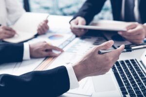 A financial advisor uses a computer and points at graphs during a meeting.