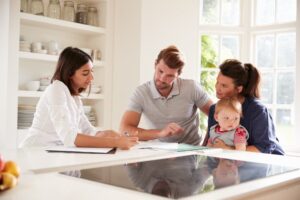 A young couple holds their baby while talking to a female financial advisor.